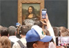 Man dressed as old woman throws cake at Mona Lisa painting